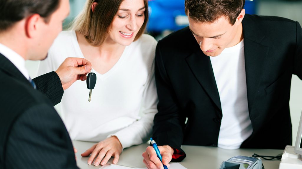 Couple signing a New Car Financing agreement and being given the keys to the SUV