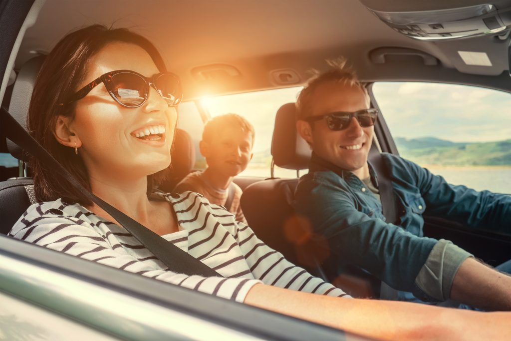 Family laughing together in ?SUV while driving on summer road truo
